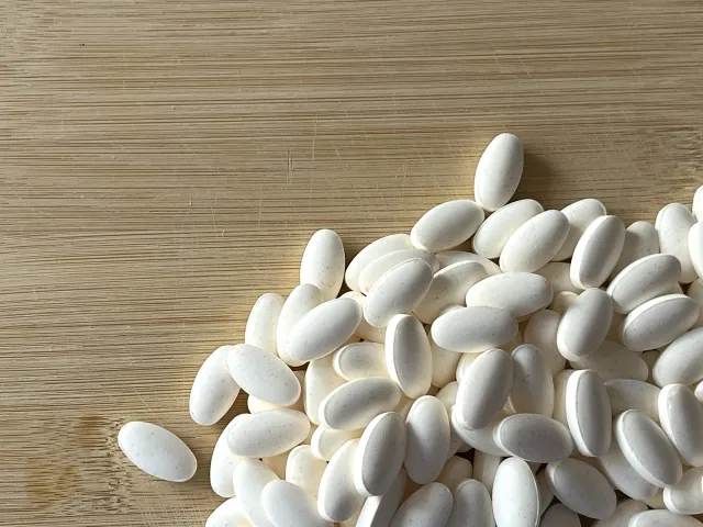 白い錠剤サプリメントが大量に並んだ写真。過剰摂取による腎臓への負担を示すイメージ。