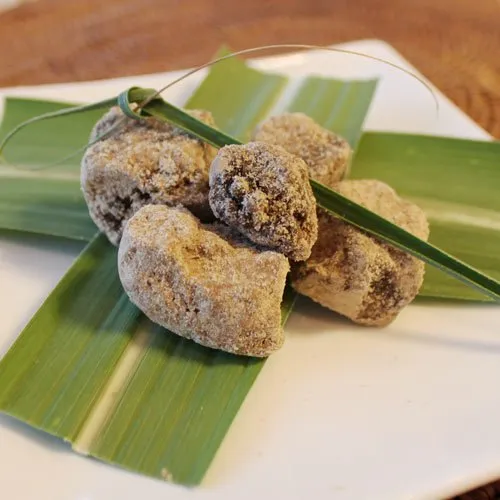 黒糖の塊が緑の葉の上に並んだ写真、補血剤として貧血や冷え性に良い自然な糖