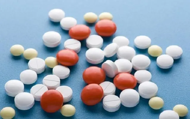 散らばった赤・白・黄色の錠剤 - ステロイド剤の副作用（顔のむくみなど）を象徴