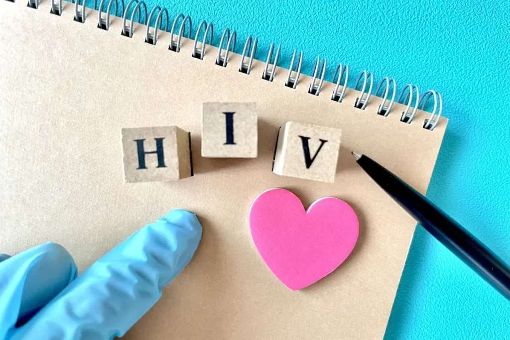 HIVと書かれたメモ帳と医療用手袋を着けた医師の手