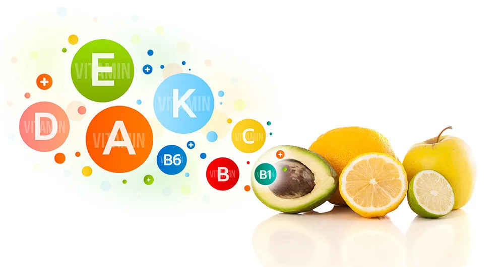 みかんやりんごなどの新鮮な果物の横に、ビタミンA・B・C・D・K・B6と書かれた丸い標識。自然食品の栄養を表す