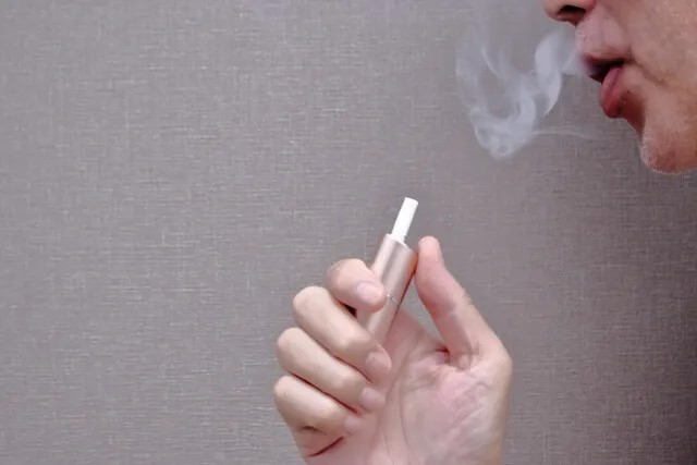 電子タバコを吸い煙を吐く男性のイメージ。タバコと肺がんの関連性や肺気腫の漢方治療を解説する記事のアイキャッチ。