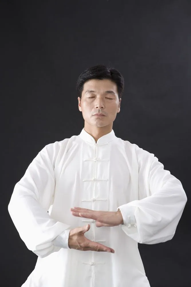白い気功服を着た男性、静かなポーズで精神集中