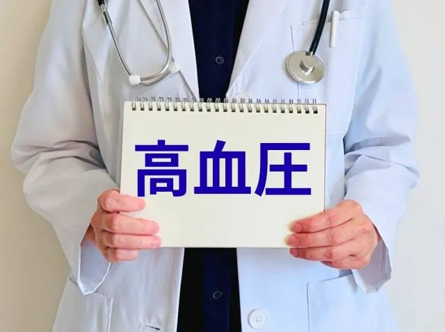 白衣を着た医者が「高血圧」と書かれた板を持って立つイラスト