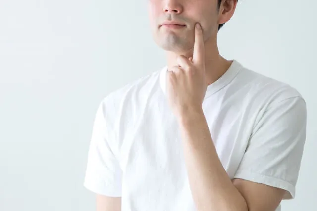 半袖姿の男性が顔と顎の赤いニキビを指で指摘し、不安げに眺めている様子。コンビニ食の影響を示す健康警告のイラストレーション。