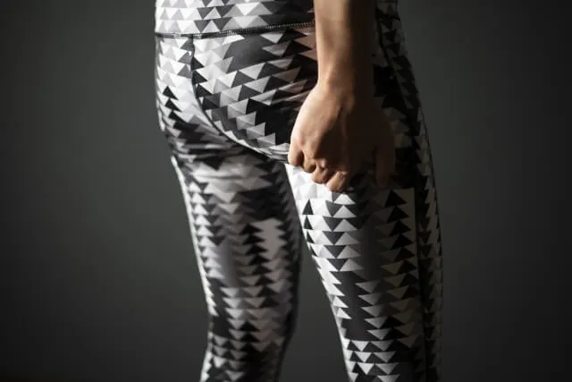 シマウマ柄のヨガパンツを履いた女性が太もも後ろの痛みを触っている様子