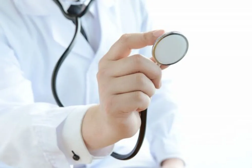 男性医師が白衣を着て聴診器を前に差し出し、患者を診察する準備をしている様子