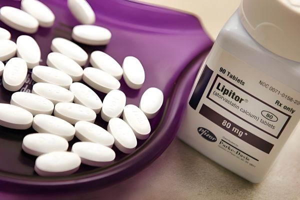 白い皿に盛られたリピトールの白い丸薬と、LIPITORと書かれた薬瓶が並んだ写真。