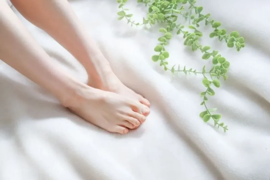大腸がん・乳がん手術後の冷え性が漢方で改善した女性の足元。足が温まり、ぐっすり眠れるようになった様子を象徴するクローズアップ画像。緑の葉で自然治癒力を表現。