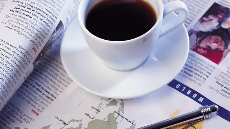 本の上に置かれたコーヒーカップとペン