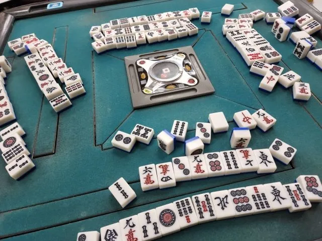 麻雀テーブルに牌が倒れている様子。治療の「賭け」に挑む比喩