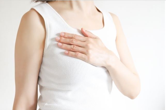 右胸に手を置く女性が漢方薬による乳がんのしこり治療を象徴