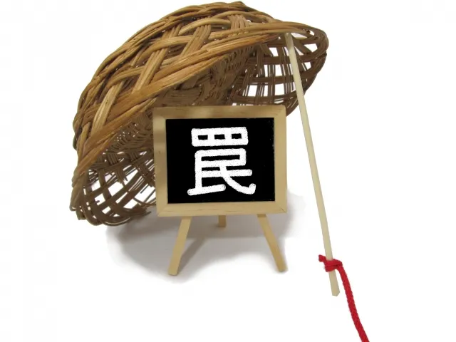 「罠」と書かれた木製看板とザルのイメージ