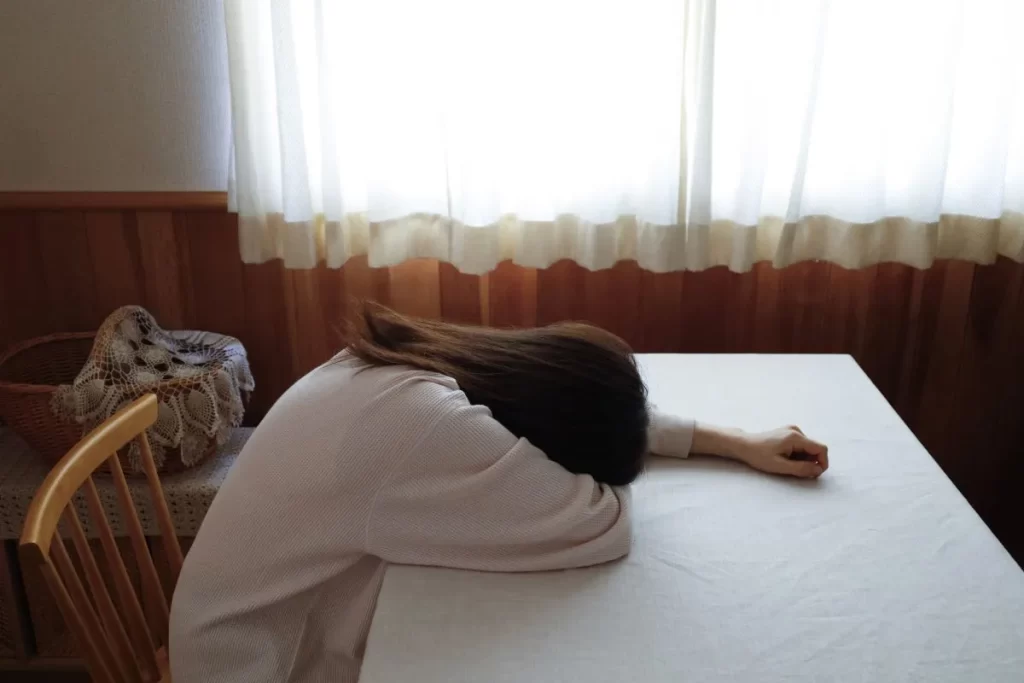 倦怠感でテーブルに突っ伏している女性の写真