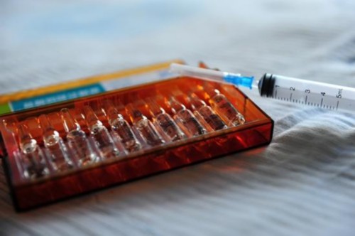 モルヒネの薬瓶と注射器が木製のケースに収められている写真。鎮痛剤の過剰使用による健康リスクを象徴。