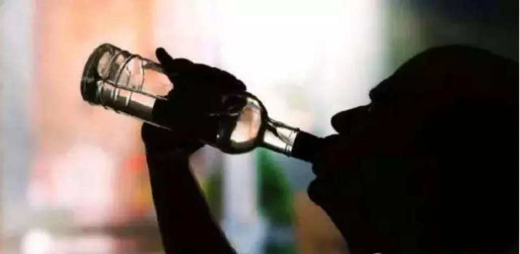 酒瓶を持ち上げて一気飲みする人物のシルエット。背景は白。