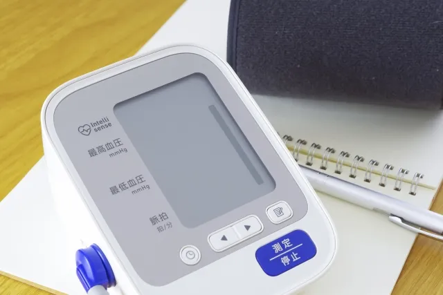 血圧計とメモ帳、ペンが置かれた高血圧治療のイメージ