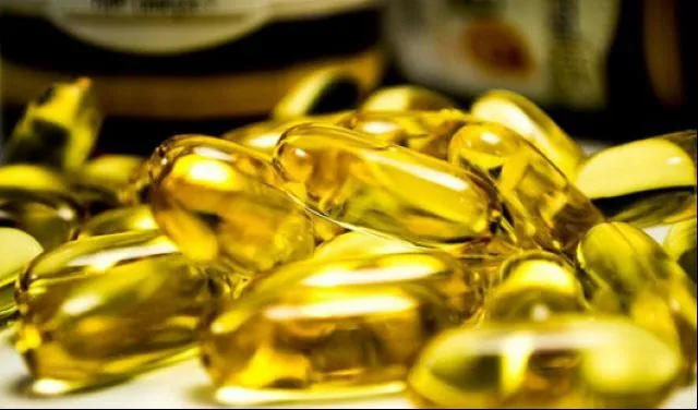 黄色く透明なビタミン・サプリメントカプセルが大量に散らばった写真