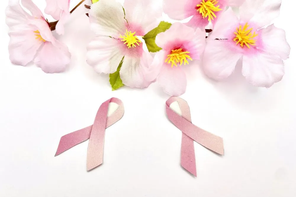 ピンクリボン2つとピンクの花が並ぶ乳がん啓発イメージ。漢方治療で回復の希望を象徴。