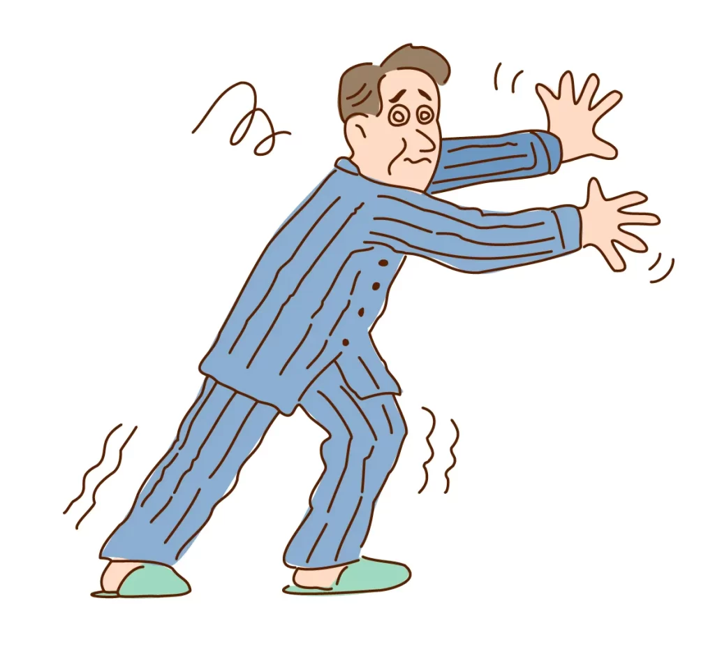 頭蓋咽頭腫で視力障害と全身の激痛に苦しむ男性患者のイラスト。青いパジャマとスリッパ姿で壁に手をつきながらよろよろと歩く様子を表現。目は渦巻き模様で視力低下を、体の周囲に震えの波線で痛みと衰弱を示している。