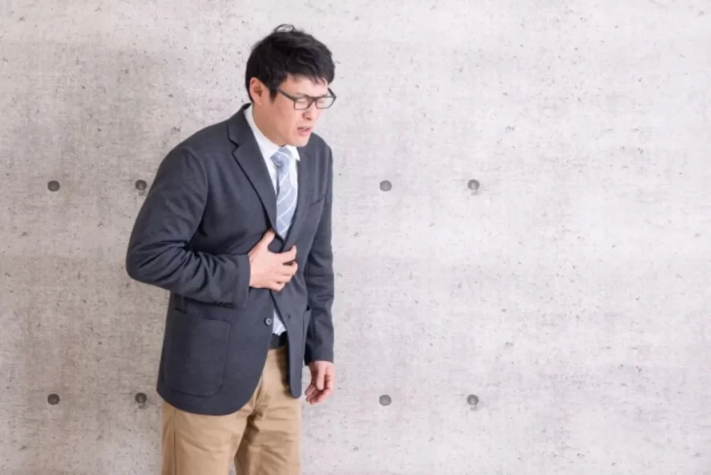 胃痛でみぞおちを押さえて苦しむスーツ姿の男性