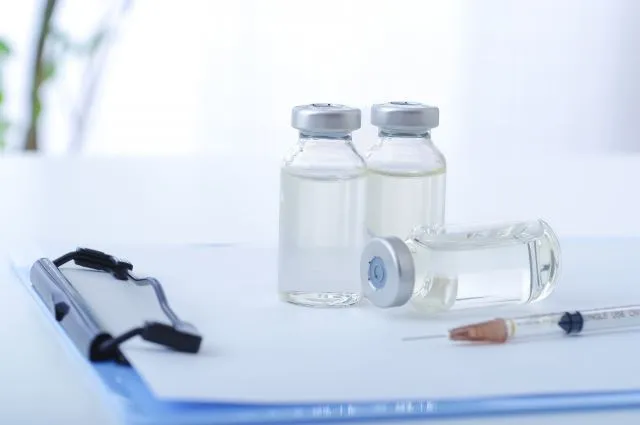 抗がん剤の注射器と薬瓶がカルテの上に置かれたイメージ写真。西洋医学のがん治療を象徴