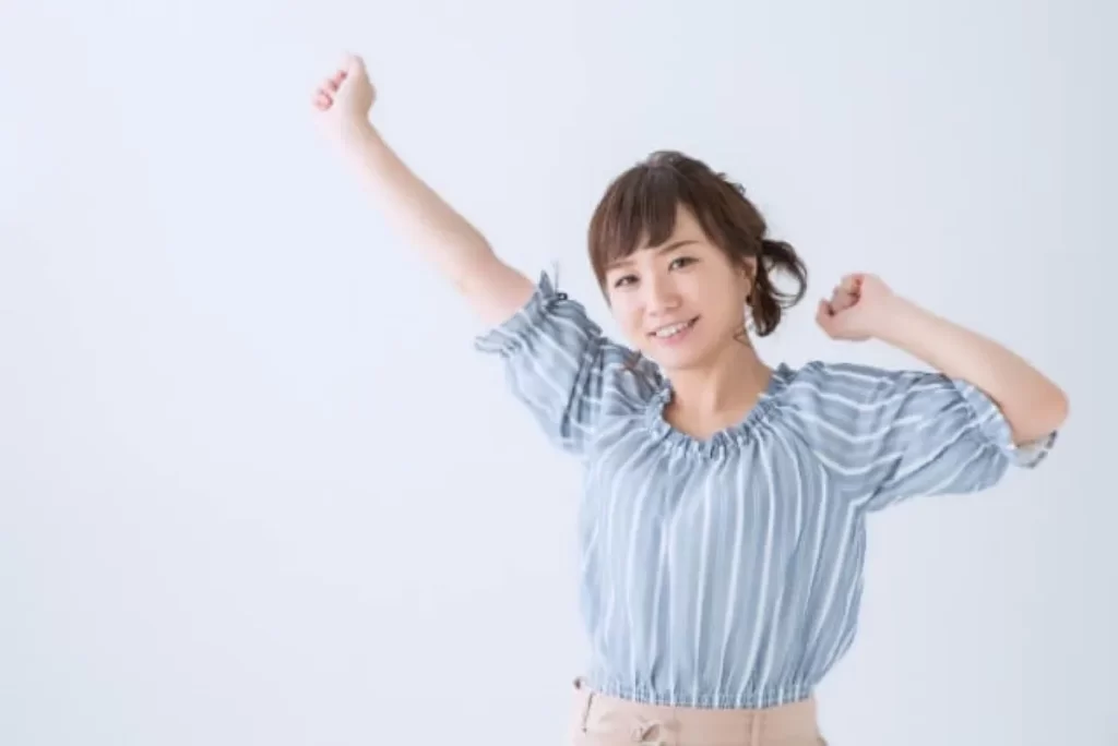 ボーダー柄の半袖を着た女性が、喜んで両手を上げて笑顔になっている様子