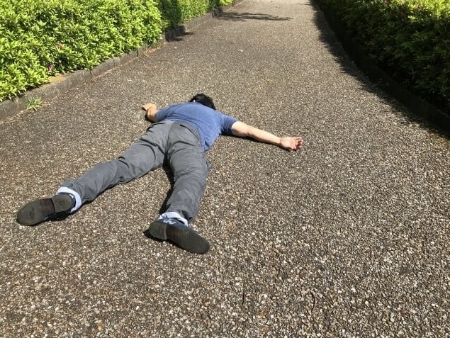 アスファルトの道で突然失神し、うつ伏せに倒れた男性の様子。中医学の臓厥症状を象徴する画像。
