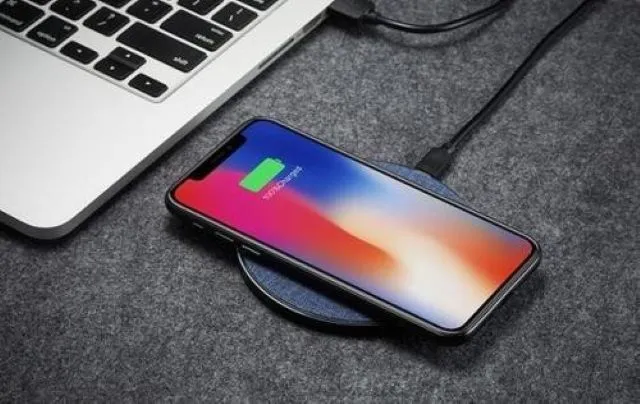 ノートパソコンの横に置かれたワイヤレス充電パッドでスマホを充電している様子