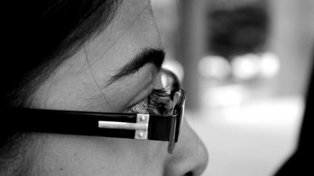 メガネを掛けた女性の目をクローズアップした白黒写真。視力回復を象徴するイメージ。