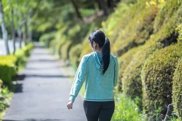 緑道でジョギングする女性の背中。痔予防に効果的な運動