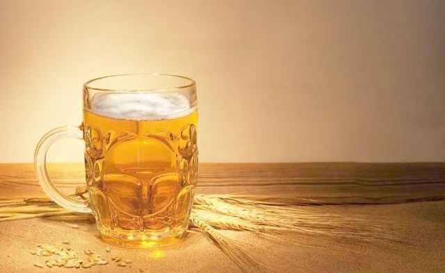 木のテーブルに置かれた透明なジョッキーに入ったビール。鍼灸治療中は飲酒を控えるべきことを示す画像。