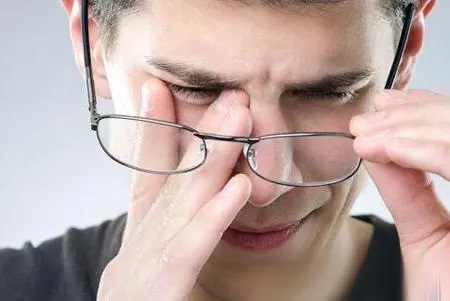 まぶたの痙攣が気になり、メガネを外して目の内側を触る男性