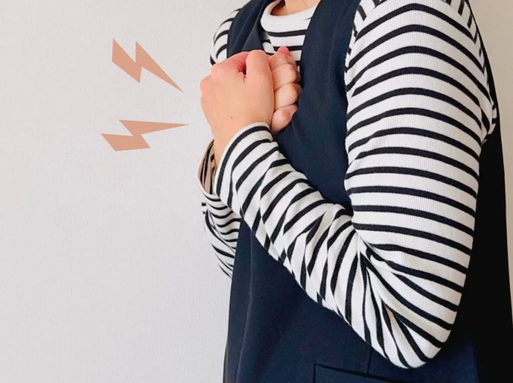 胸を両手で押さえて苦しむ女性のイラスト。胸に雷マークが2つあり、心臓発作の痛みを表現