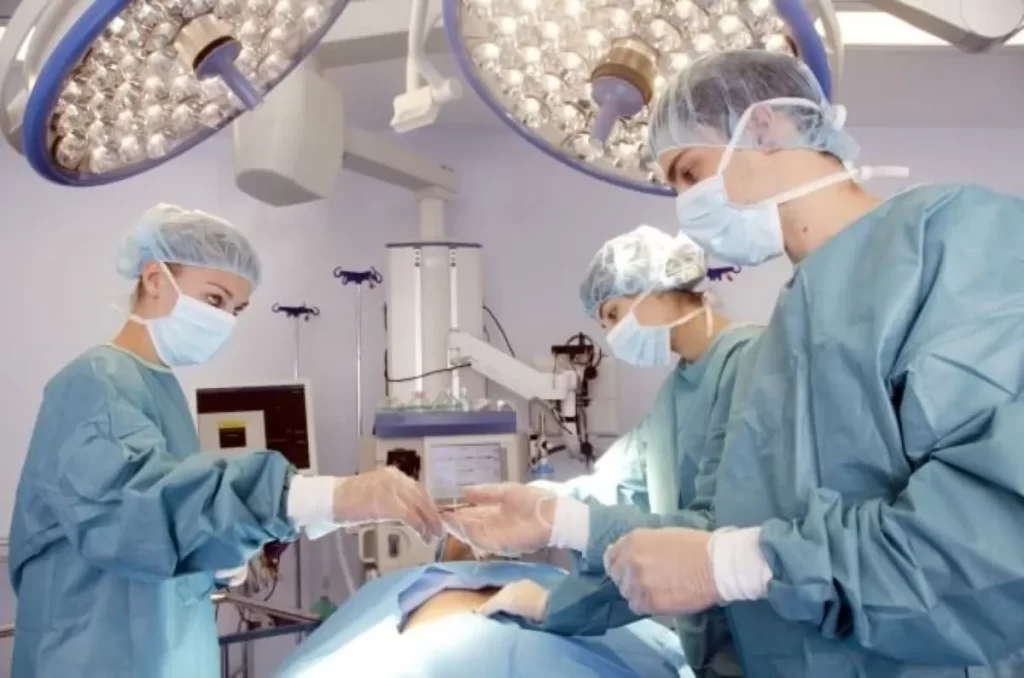 手術中の医師たちが器具を受け渡している様子。外科手術の負担や体への侵襲を示すイメージ。