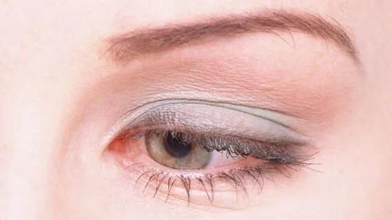 化粧した女性の目クローズアップ。眼瞼下垂の症状でまぶたが下がり視界を遮る様子。鍼治療で自然に改善可能