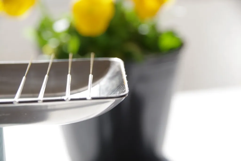 ステンレス皿の鍼と背景に黄色い花がぼやけている写真