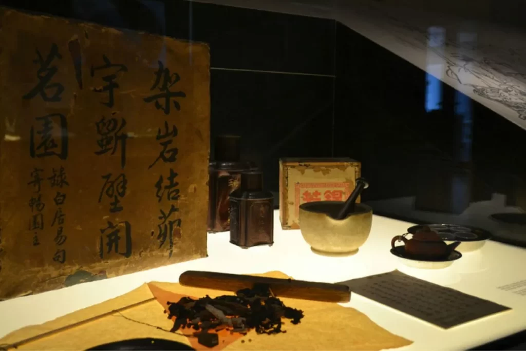漢方薬の処方箋と生薬、乳鉢、木の棒、古い文書が並ぶ伝統中医学の作業風景