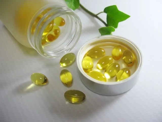 透明な瓶からこぼれた黄色いビタミン剤の錠剤