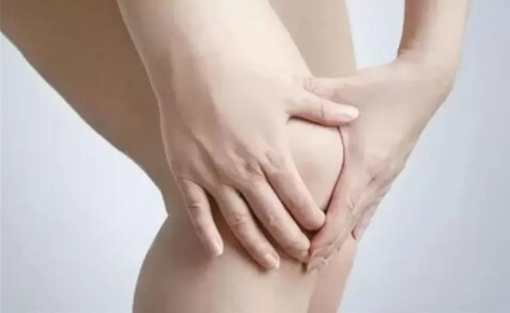 50代女性が右膝の痛みを両手で抑えている様子