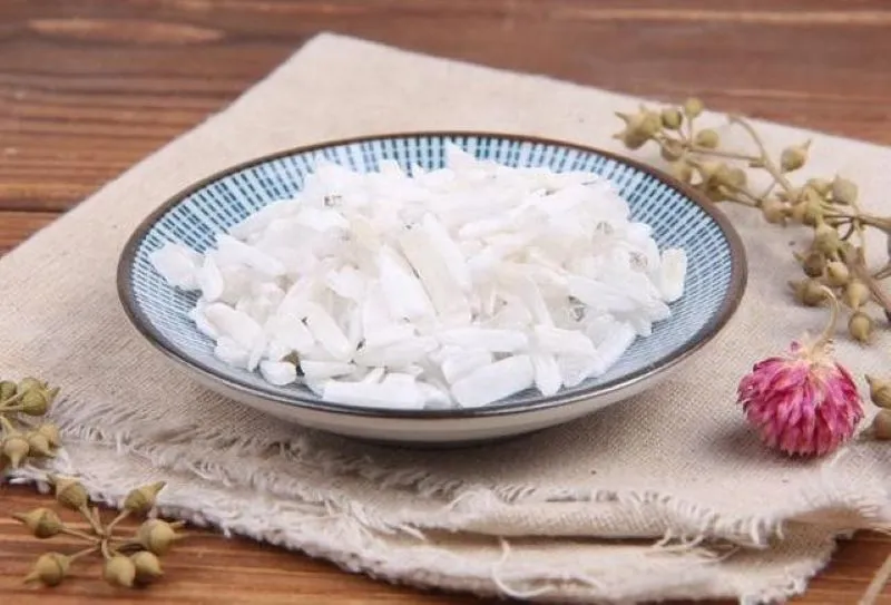 青い模様の丸皿に棒状の石膏が並び、隣に枯れ枝とピンク色の花が添えられている写真。