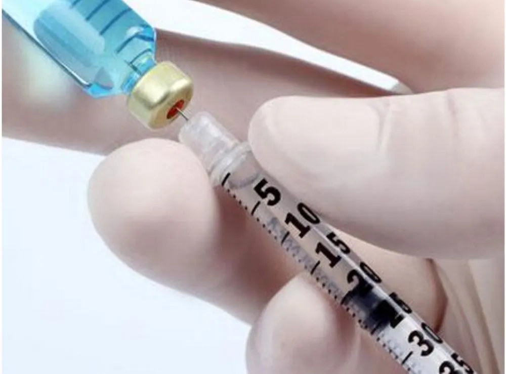 医師の白い手袋で青いワクチンを注射器に吸引するクローズアップ