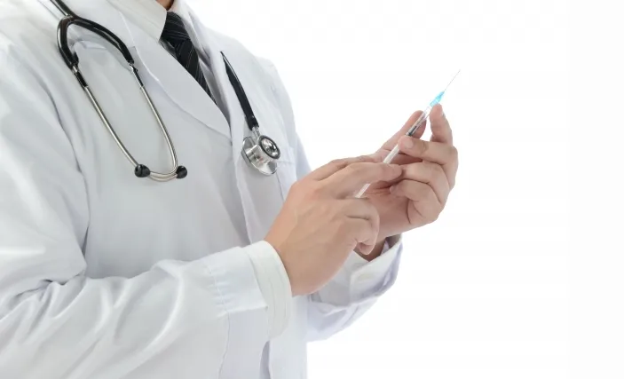 白衣を着た医師がインフルエンザワクチンの注射器を持つ画像