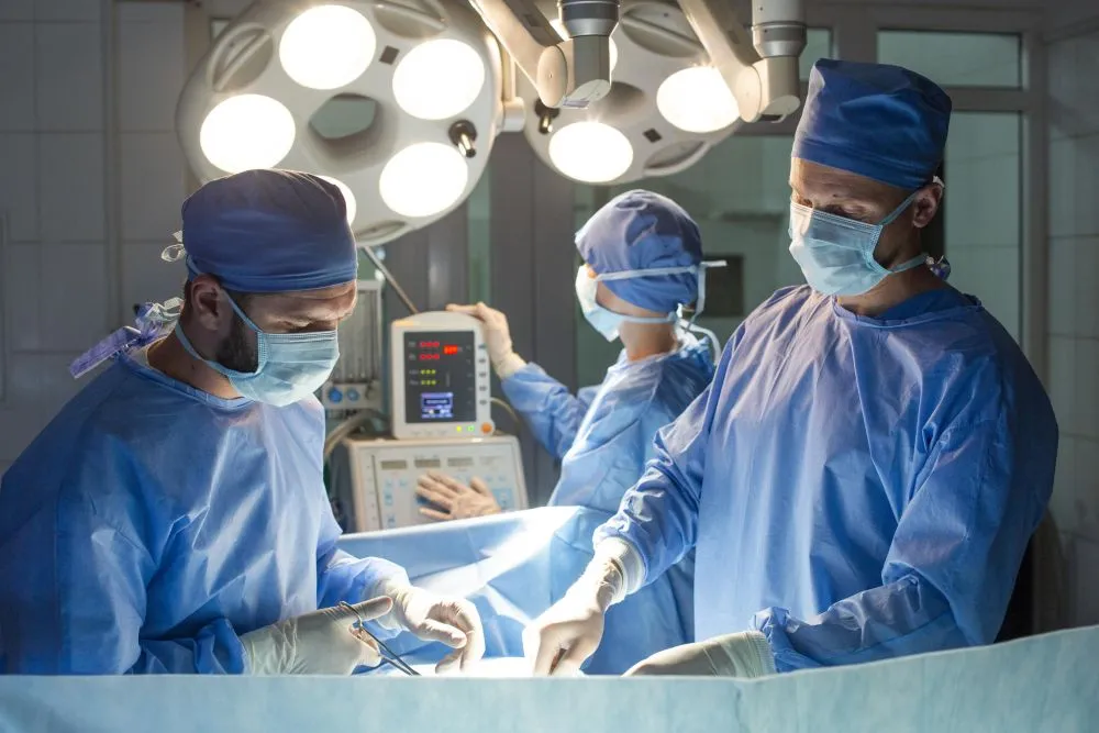 青い手術着を着た医師たちが手術室で執刀している様子