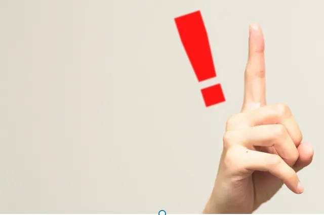 赤い感嘆符の隣で人差し指を立てる手のイラスト