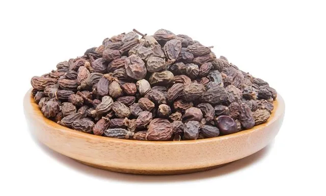 肝を潤す生薬・女貞子（ジョテイシ）。丸い木の容器に入った黒っぽい乾燥果実