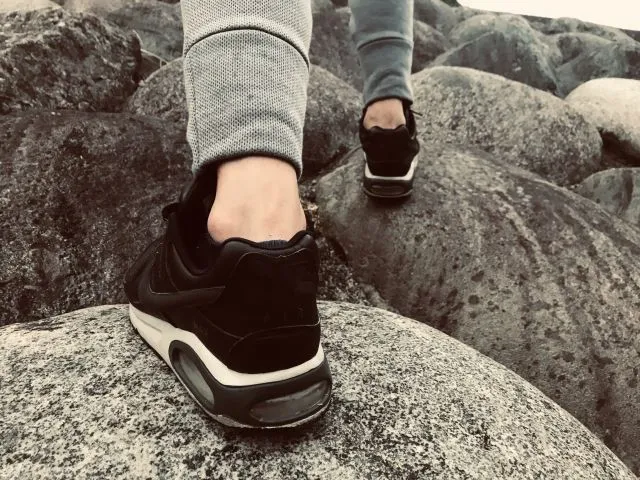 スニーカーを履いた足で岩を登る際のアキレス腱のクローズアップ写真。負荷がかかった状態のアキレス腱を示す