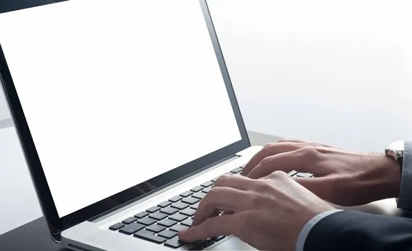 ノートパソコンを操作するスーツ姿の男性の手元。長時間作業による目の疲れをイメージした写真