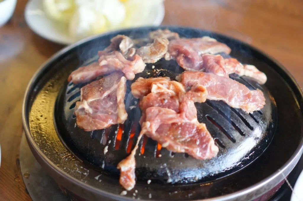ジンギスカン鍋で羊肉を焼き白い煙が立つ様子