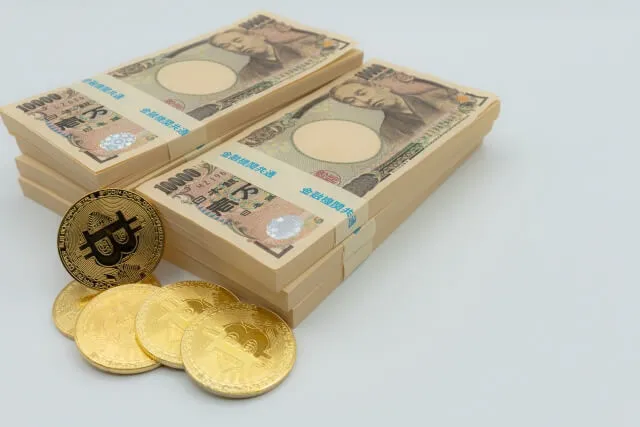 日本の一万円札の束と黄色いビットコイン風コインが重なったお金の山。商業的利益と金のイメージ